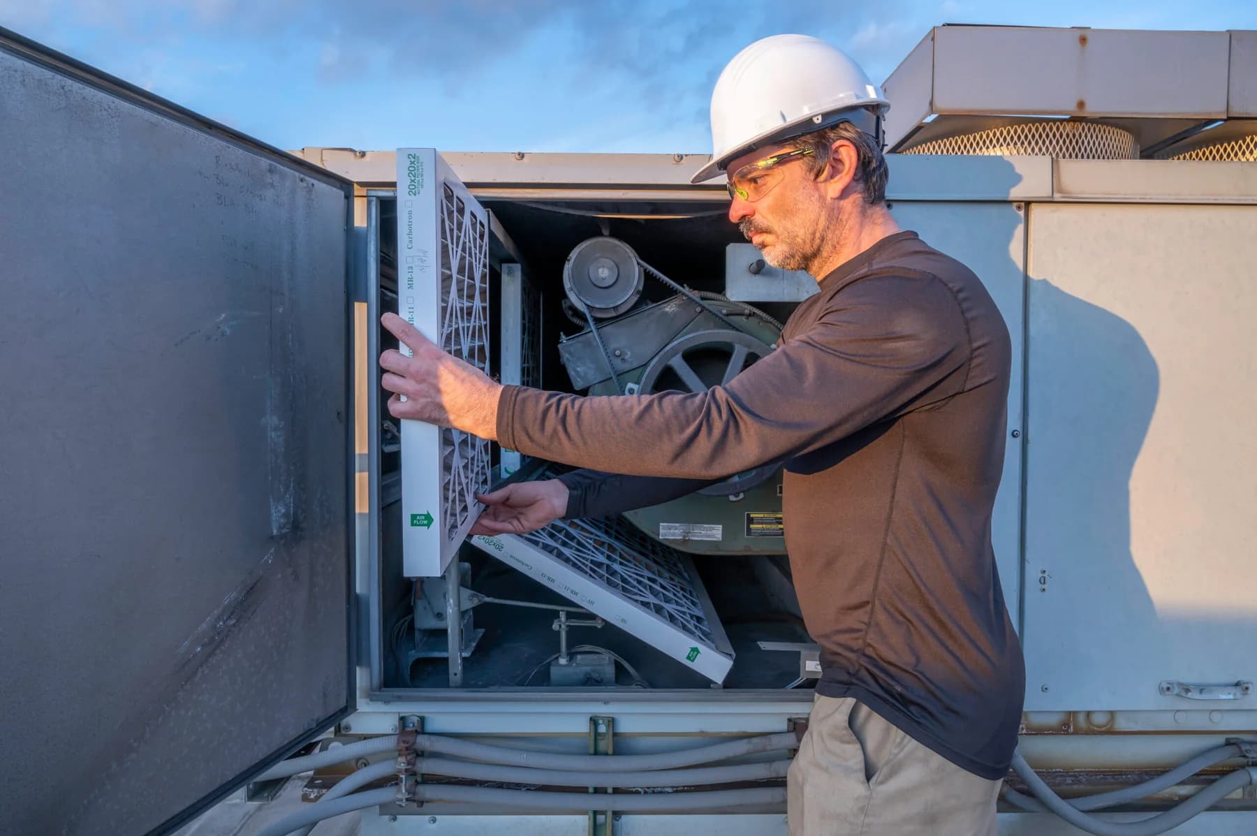 Technician inspecting an evaporative cooling unit on a roof