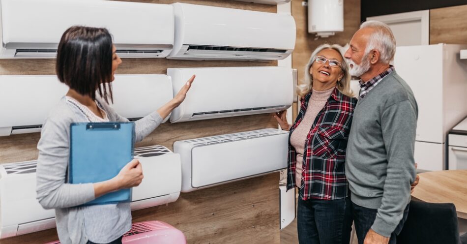 Saleswoman showing customers various air conditioners on display