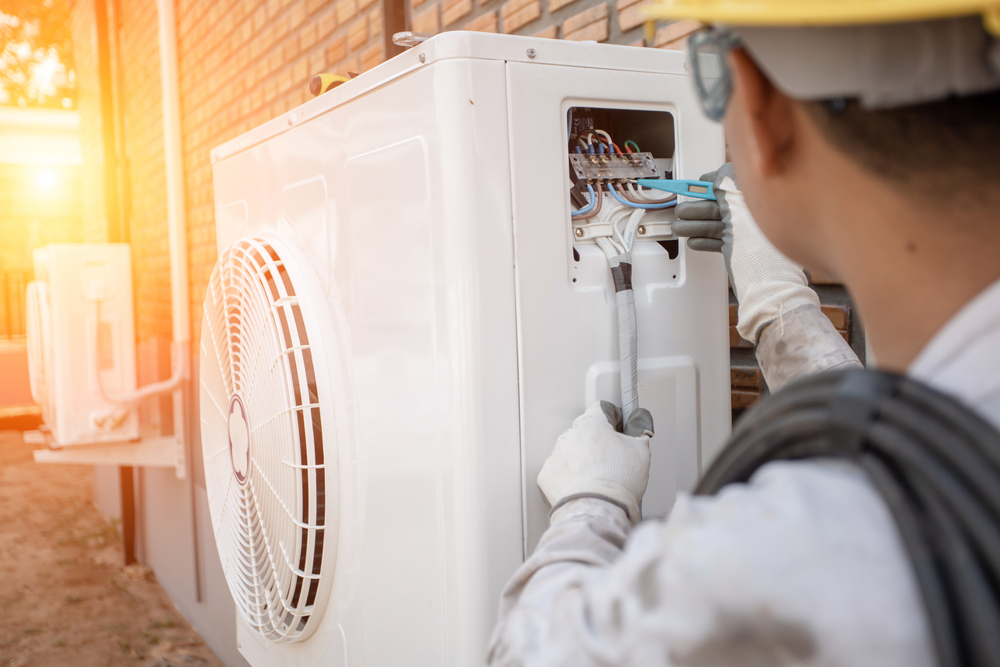 Air conditioning technician installing an AC unit outdoors