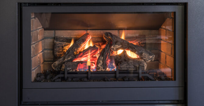 Gas fireplace logs and flames in black metal frame