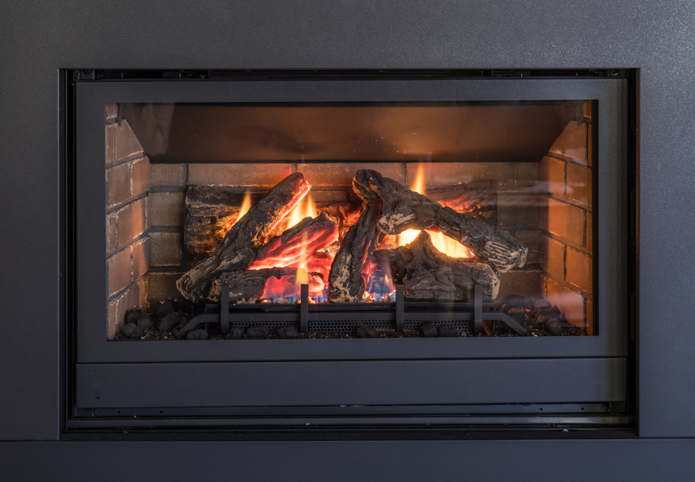 Gas fireplace logs and flames in black metal frame