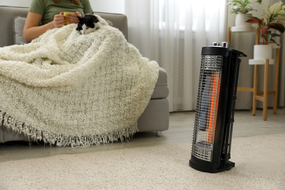 Woman with cat relaxing on a couch with a space heater