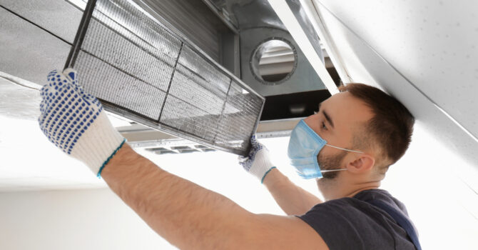 Air conditioning technician cleaning filter in split system.