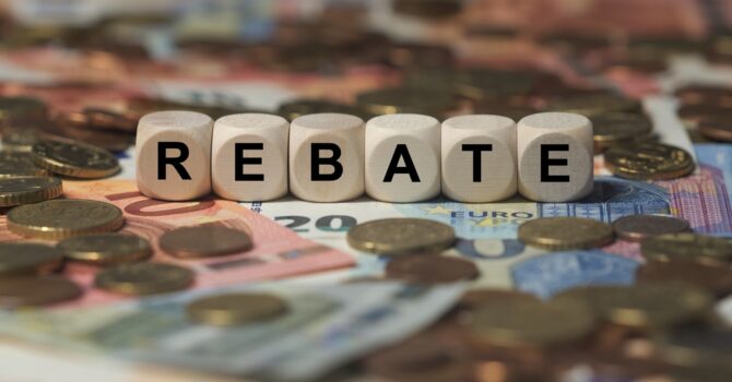 Cubes spelling the word 'rebate' sitting on a pile of coins and bills