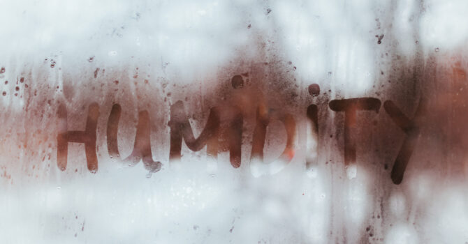 Window with a high level of condensation. The word "humidity" is written in the condensation.